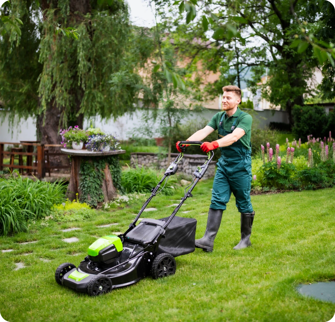 Man mowing lawn with electric lawnmower.
