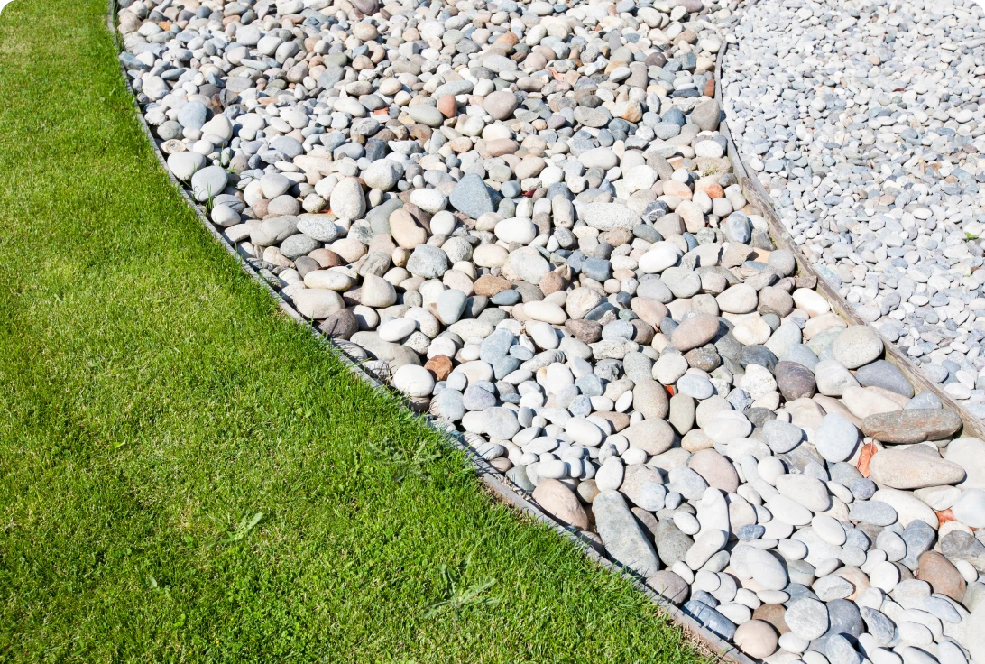 Pebble garden border beside green lawn.